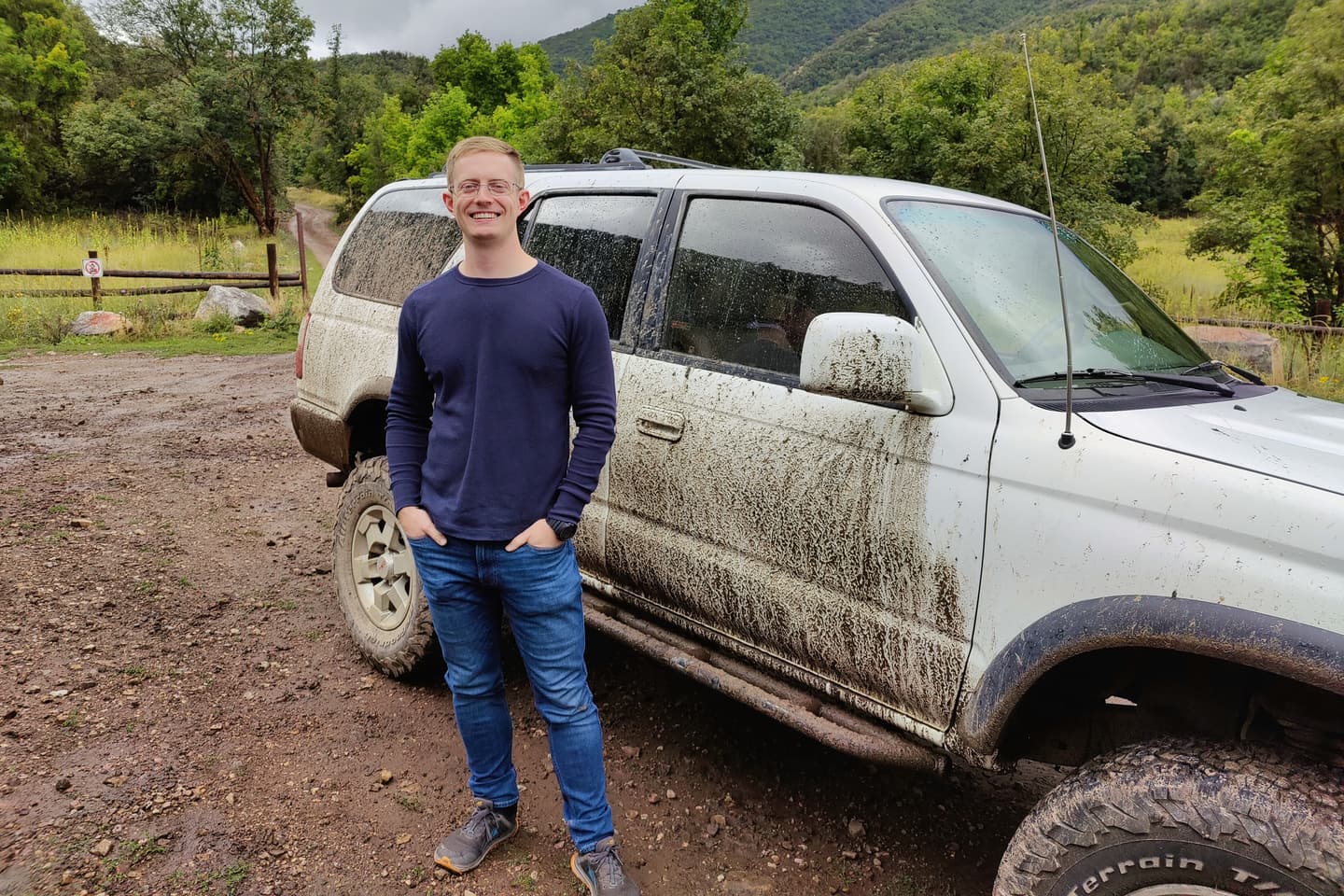 Jonathan Engle standing beside a mud-covered 4Runner on a dirt road in a Utah canyon