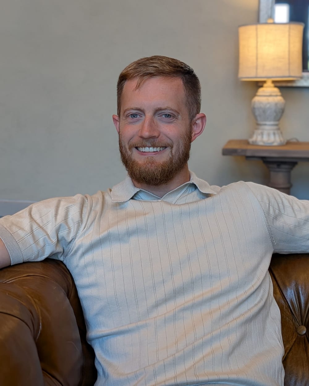 Jonathan Engle sitting back on a leather sofa, smiling